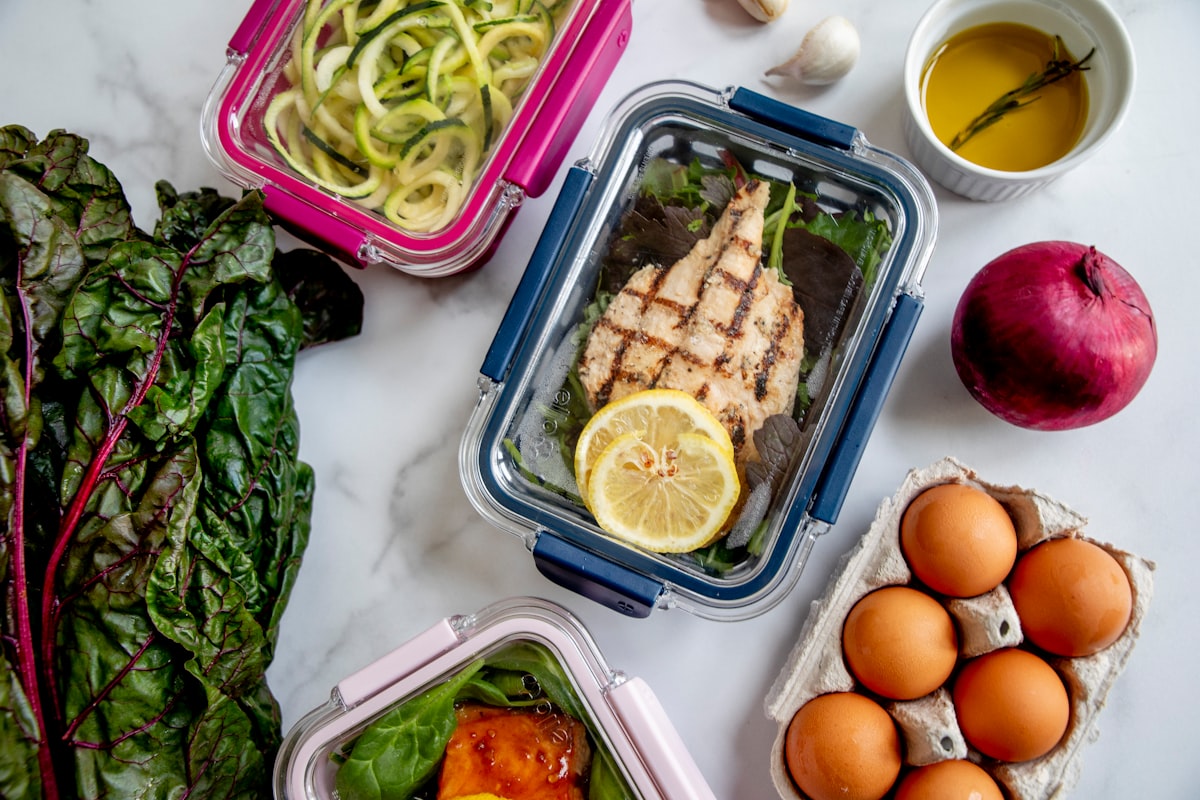 Person writing in wellness journal with healthy food and water nearby